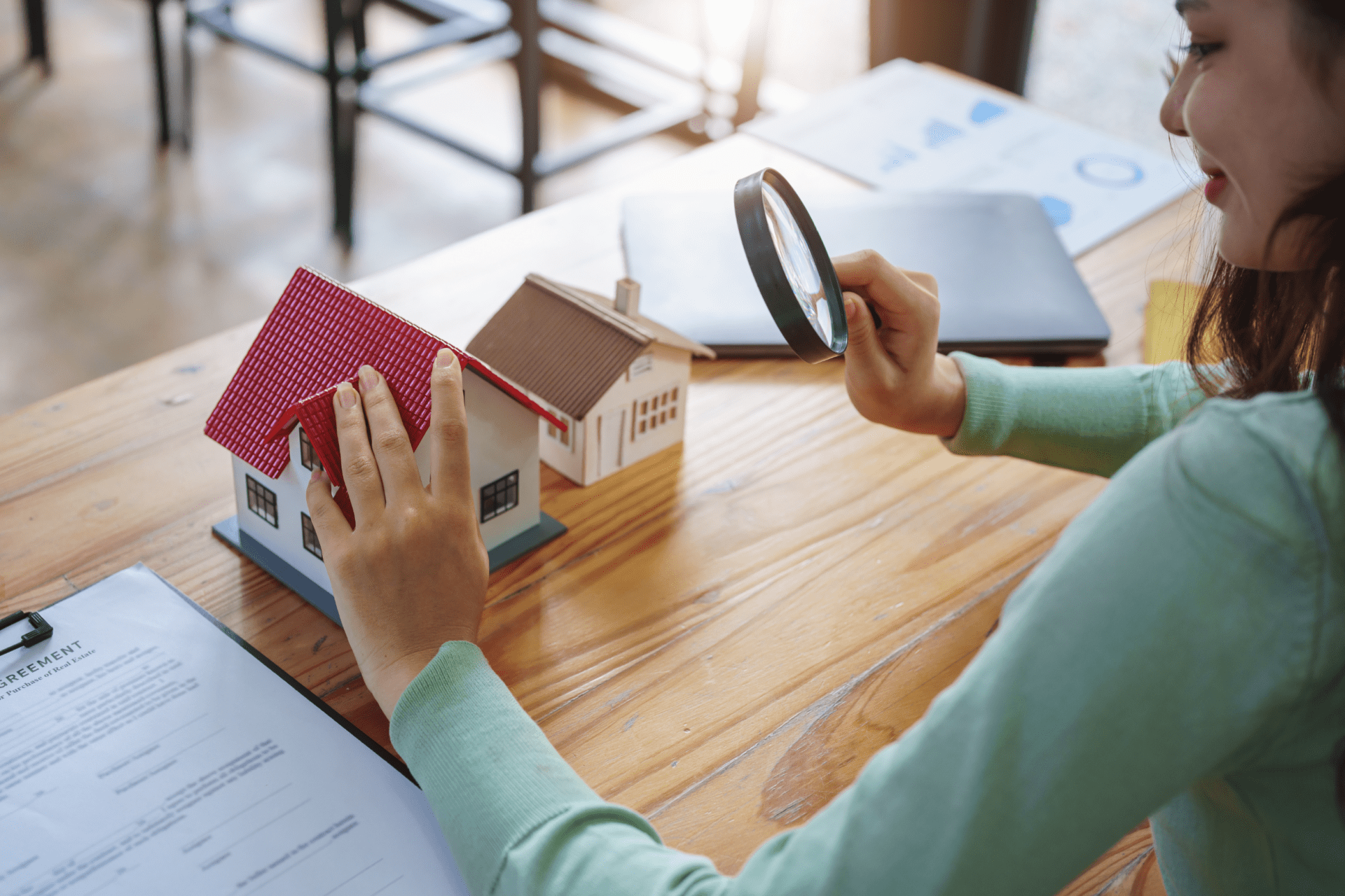 Real estate agent working with house model and holding magnifying glass.